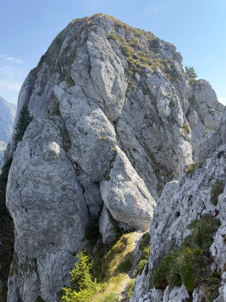 A rocky notch below the crest, with a thin rope leading away towards a descent.